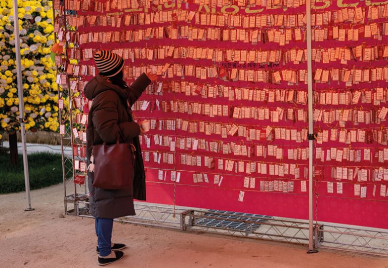 A woman hangs a note to wish for her child's success in the College Scholastic Ability Test at Chogey buddhist temple A woman hangs a note to wish for her child's success in the College Scholastic Ability Test at Chogey buddhist temple